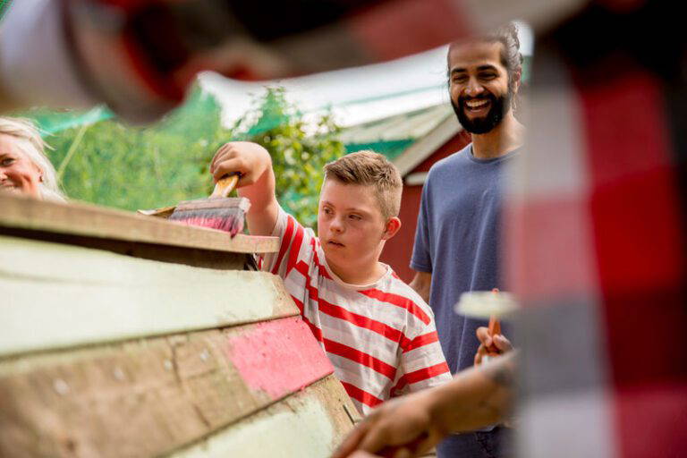 Child painting a shed with the help of a man and woman