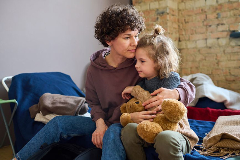 Child with teddy bear and woman on bed