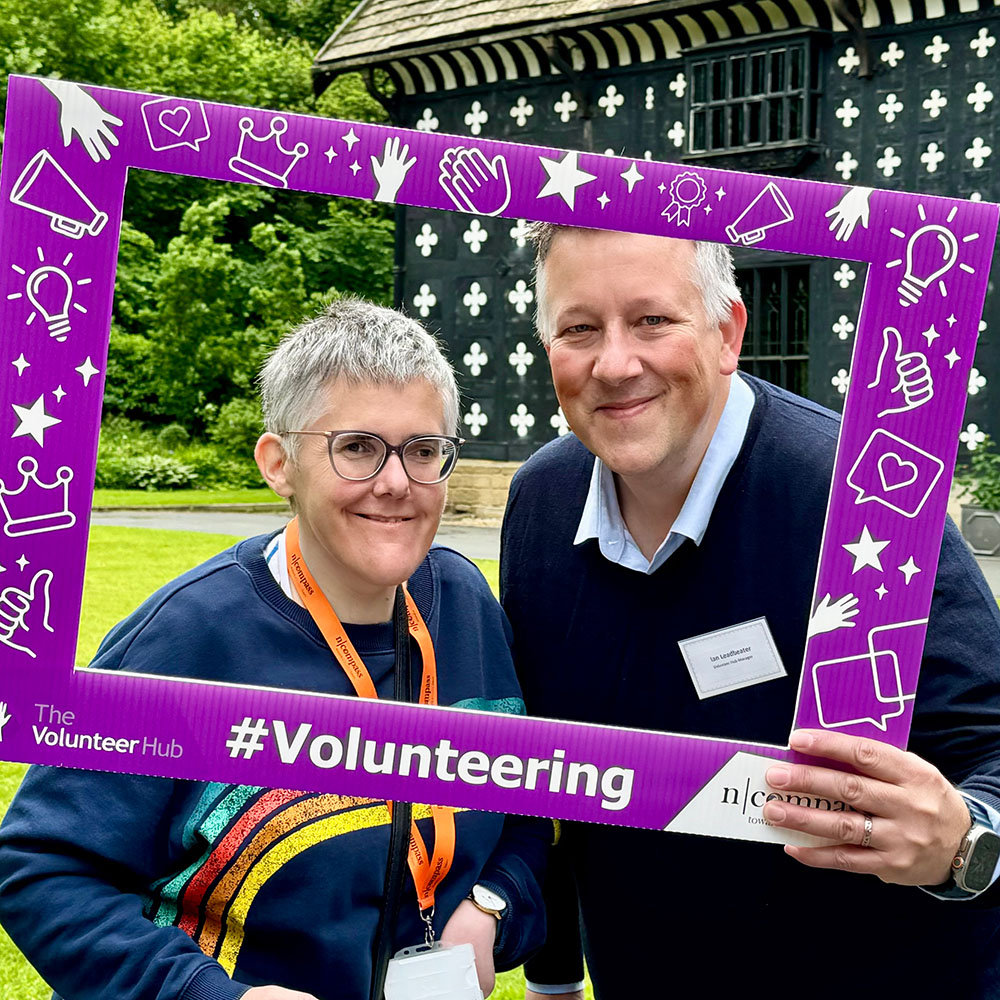 Two people holding a volunteering sign
